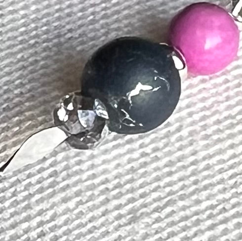 The photo is a close-up of a pointed silver headpin holding silver, silver-crackled gray, and orchid-pink beads.