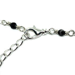 A lobster-claw clasp is attached to a length of chain. Connected to each is a wire link with a black and white bead at the center. The metals are all silver-toned, and the background is white.